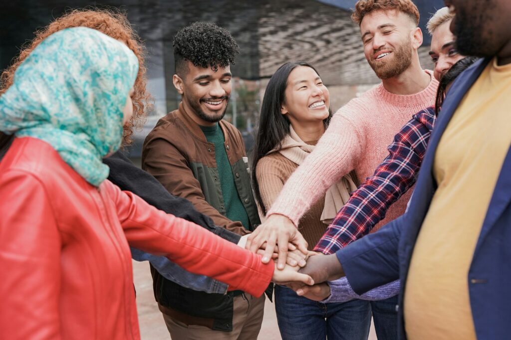 Group of young multiracial people stacking hands together outdoor